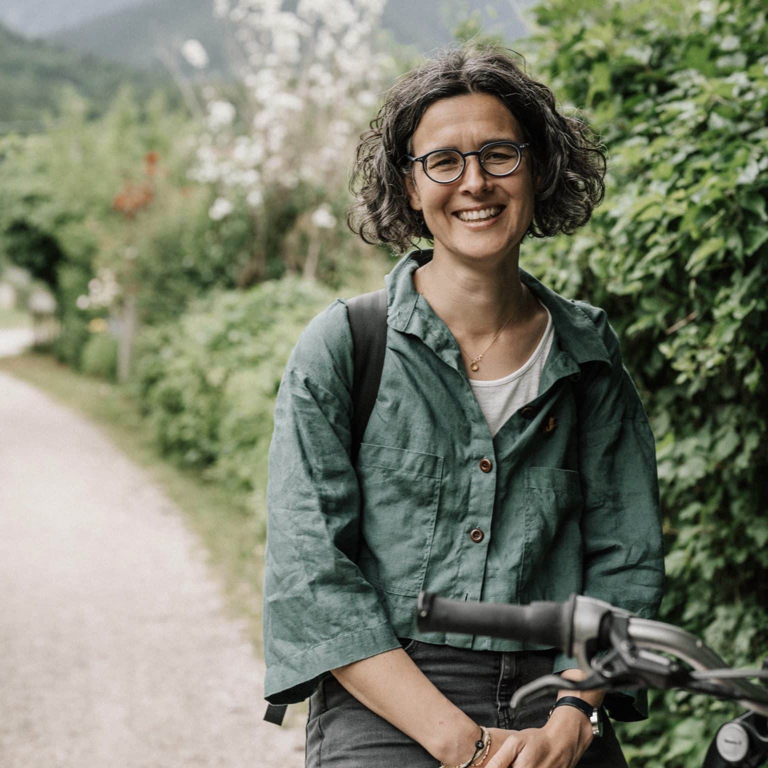 Barbara Prasch im Portrait – im Hintergrund Bäume und Büsche.