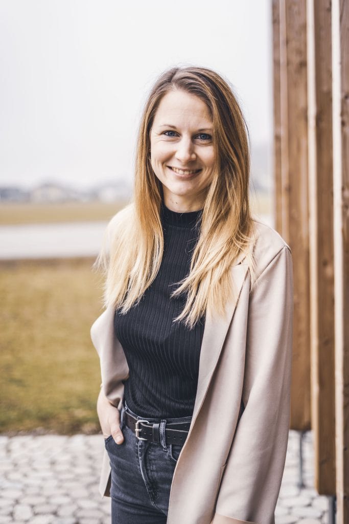 Martina Ober trägt einen beigen Blazer und eine schwarze Hose und lächelt in die Kamera.