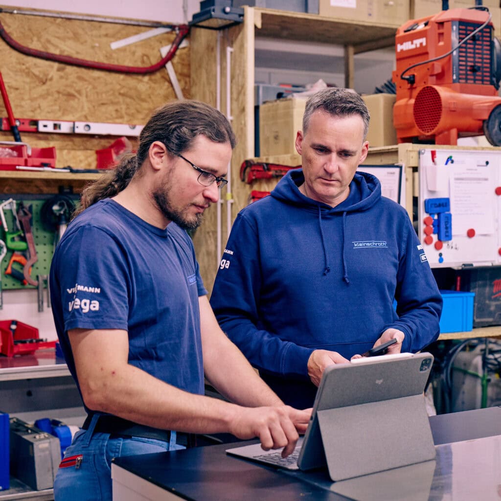 Zwei Mitarbeiter eines Handwerkbetriebs gehen am Laptop die aktuellen Themen durch.